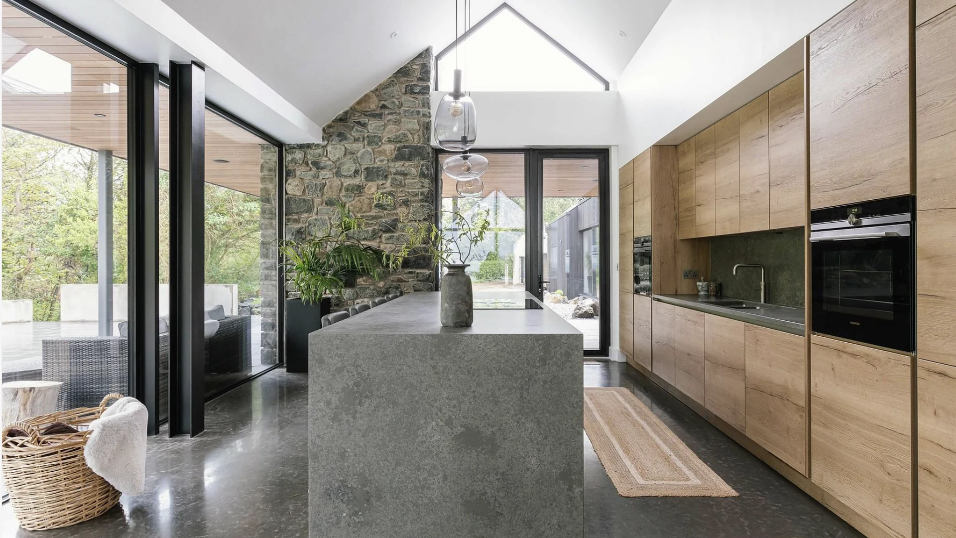 Renovated open-plan kitchen with oak cabinetry, a stone island and full-height glazing